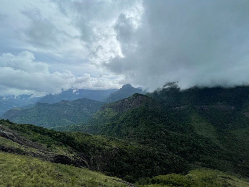 Majestic aerial view of lush green mountains enveloped by a cloudy sky.