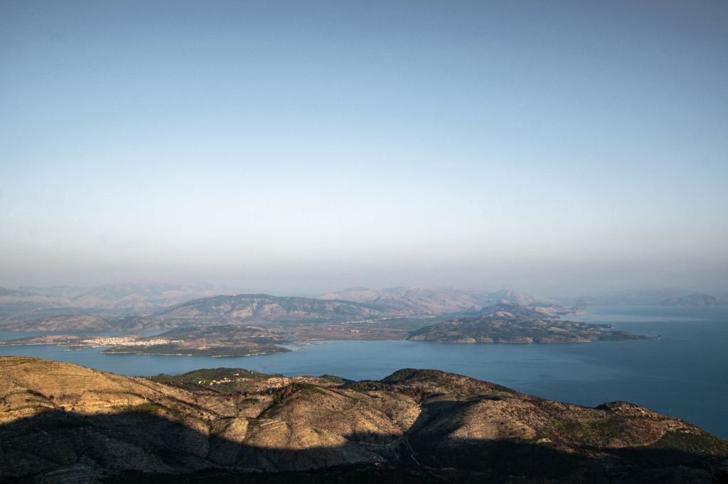 Expansive view of coastline and mountains under a clear sky, perfect for travel inspiration.